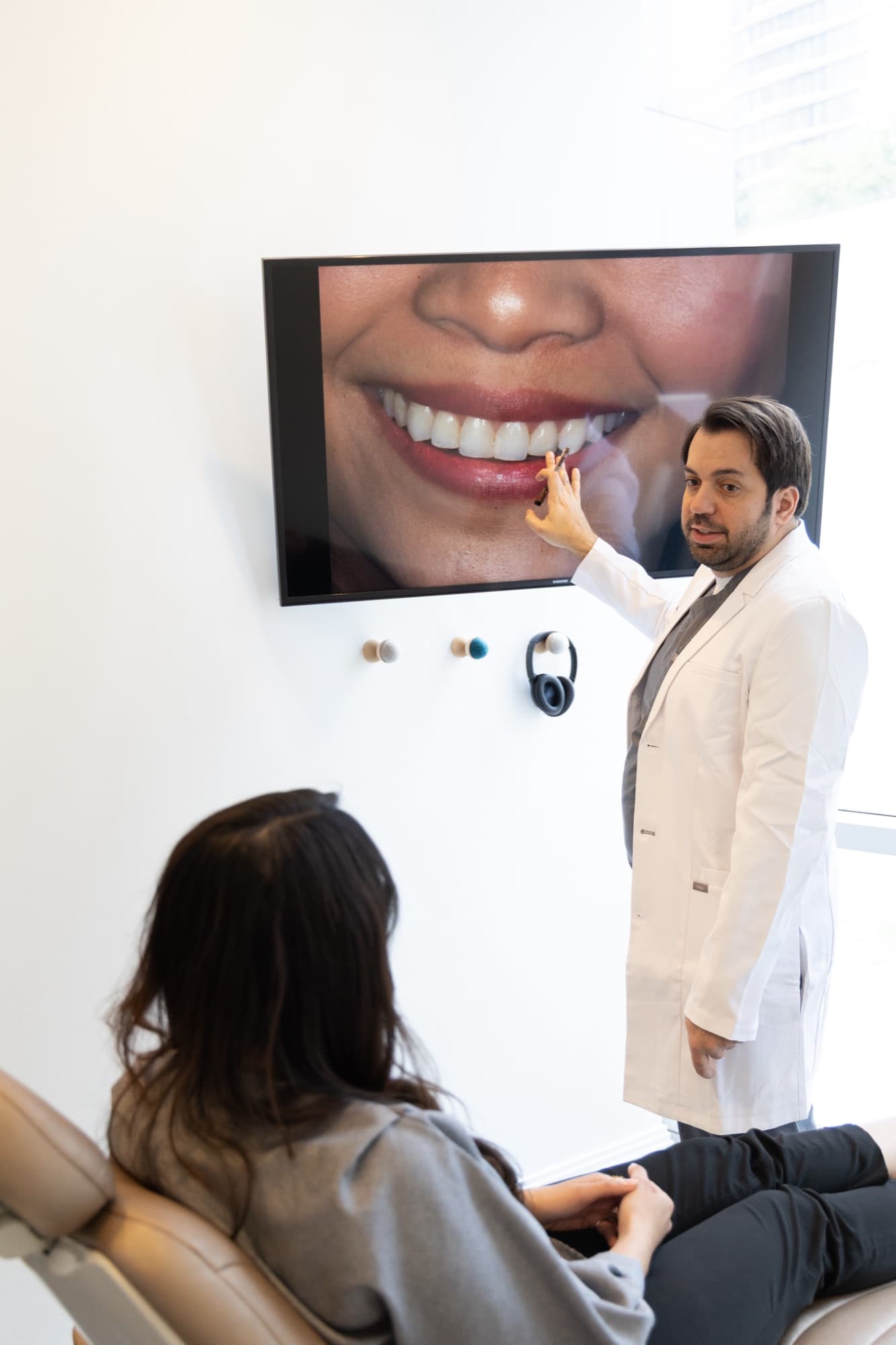 Dr. Atassi pointing at a smile photograph on the wall screen